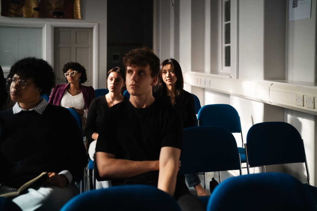 a group of students sit listening to a lecture in progress.