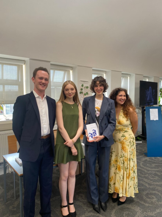 Four people stand together smiling at the camera