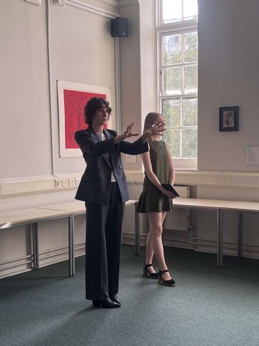 Two people stand in front of an artwork hanging on the wall