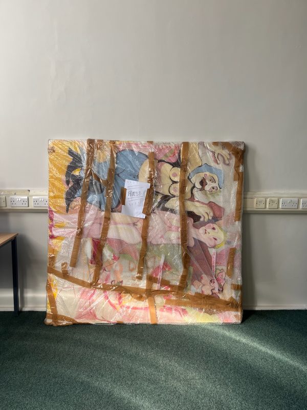 A work wrapped and propped against a blank wall