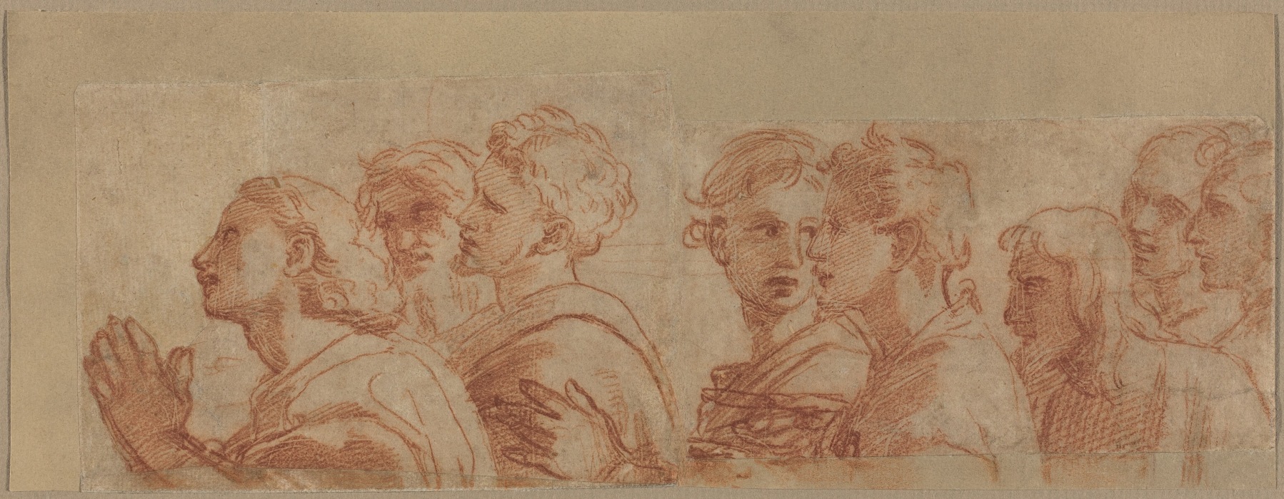 This drawing by Raphael is a sketch of several people facing the left, depicted from the chest up. The individuals are standing together in a group. Their hair is in a variety of styles, and they are dressed in draped garments. The person at the front of the group has their hands clasped together in front of their chest. The background is plain beige paper, and the lines of the drawing have been done in red.