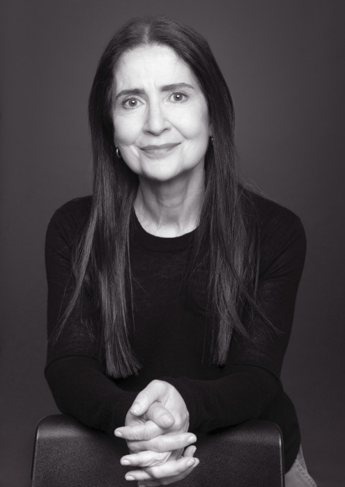 Black and white photograph of Lynda Nead, smiling with her hands clasped in front.