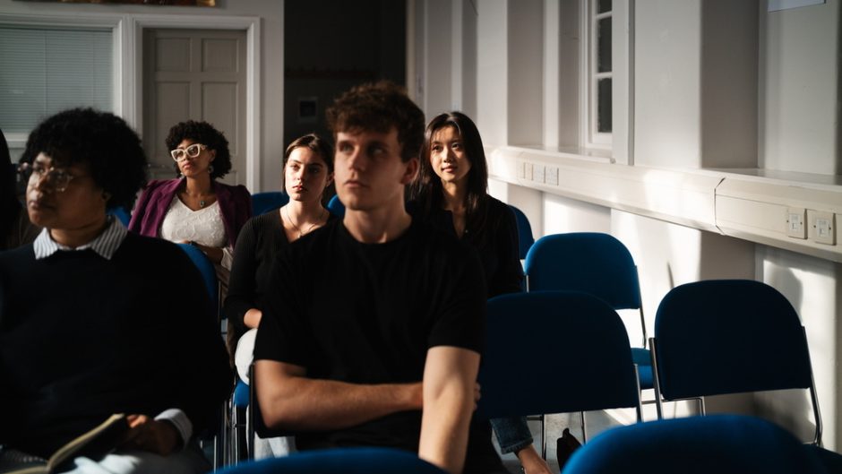 a group of students sit listening to a lecture in progress.