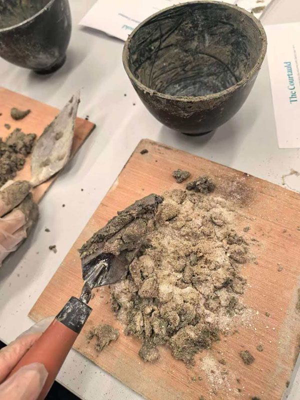 Earth mixed together with a trowel on a wooden board.