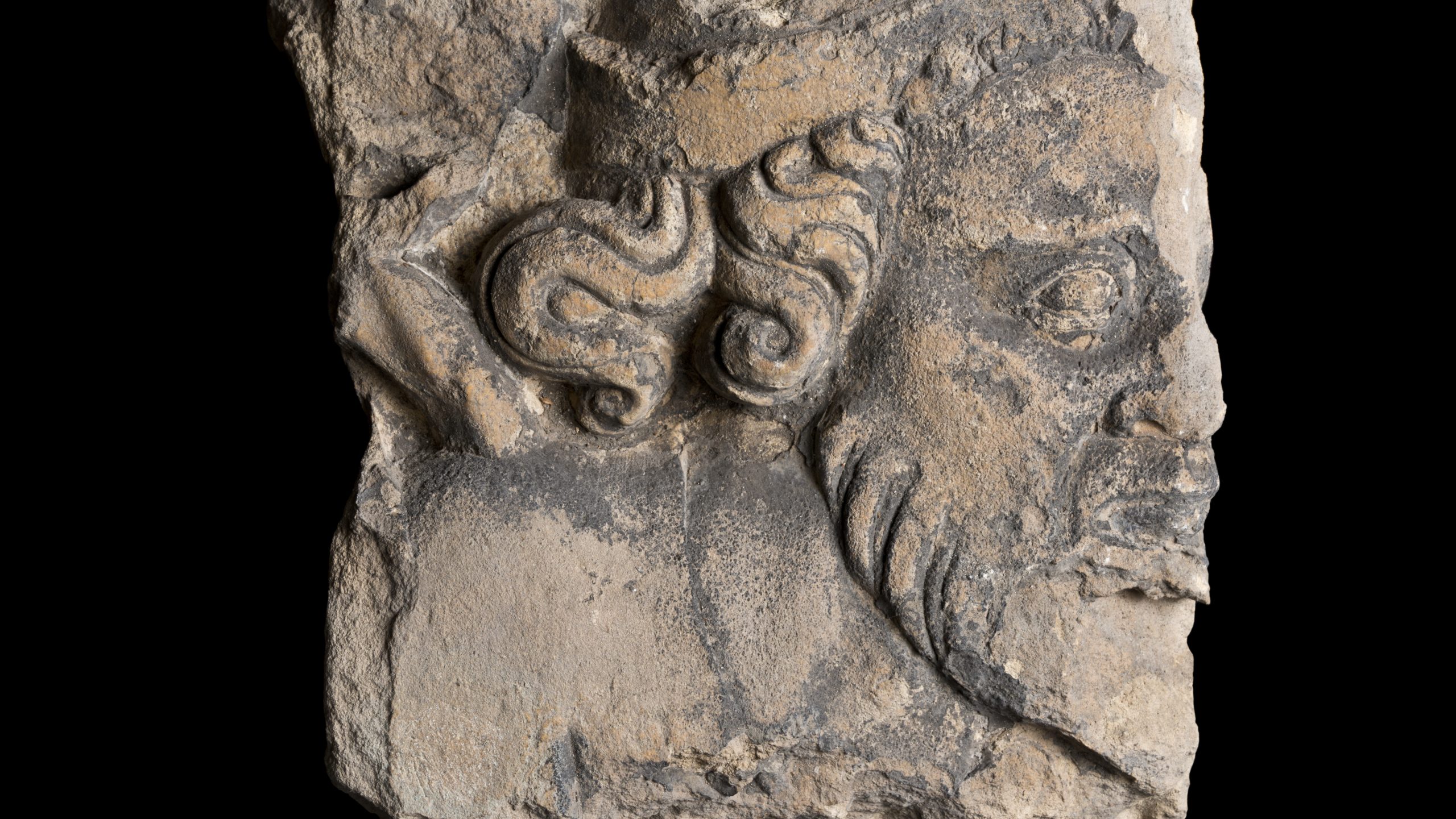 A broken piece of stone carved with the profile of a man's face
