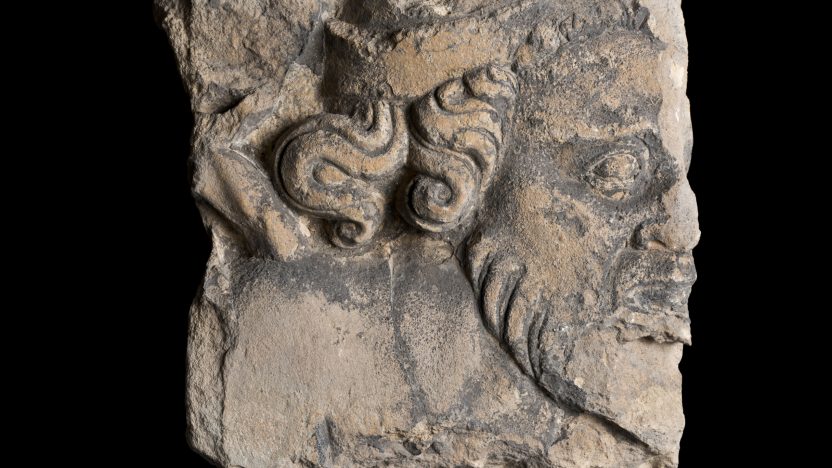 A broken piece of stone carved with the profile of a man's face