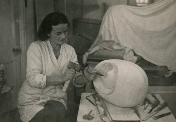 Black and white photograph of Hepworth carving Eidos, a round sculpture, in her studio in Cornwall.