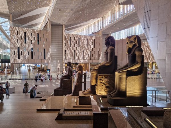 Statues of seated figures in the main reception of a museum: a big, airy space full of light and people.