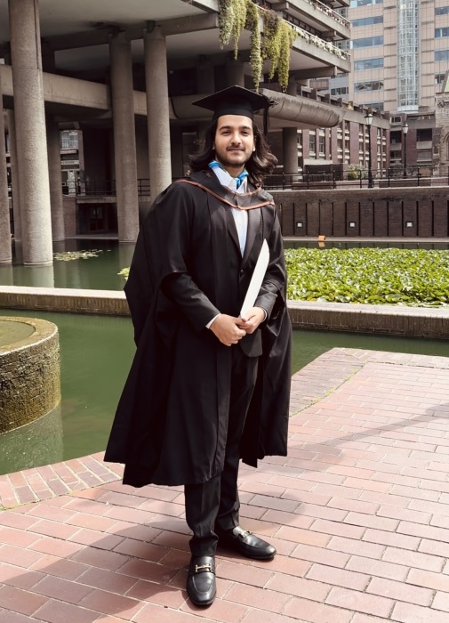 A man in cap and gown holding a graduation certificate