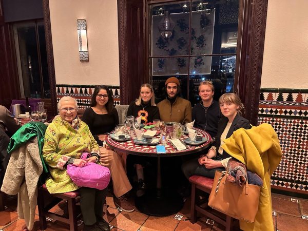 A group of people sit around a round table, smiling for a photograph
