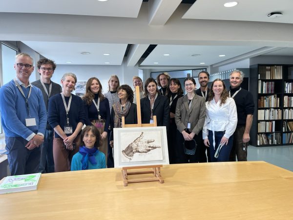 A group of researchers stand behind a work on paper as part of a GAG research visit to Teylers Museum in Haarlem, the Netherlands.
