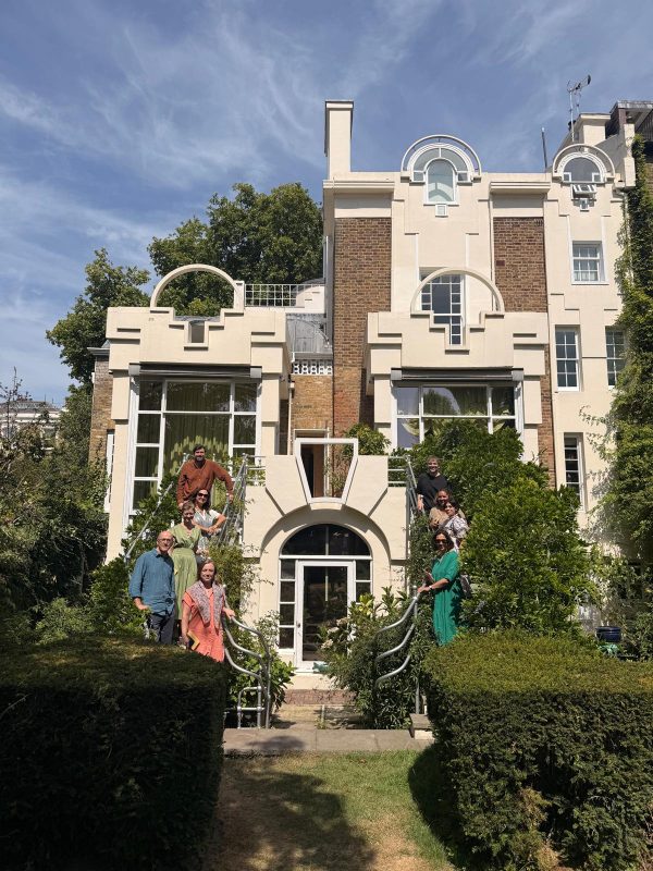 Members of the Interrogating Heritage research Cluster stand on the stairs leading into the garden of The Cosmic House