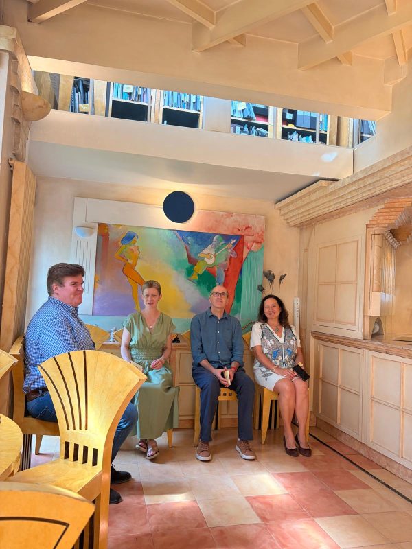 a group sit and converse inside a brightly decorated room at The Cosmic House