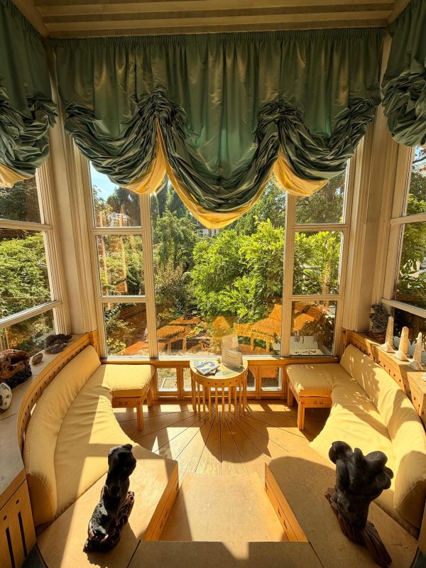 Large sunny window with green billowing drapes at The Cosmic House