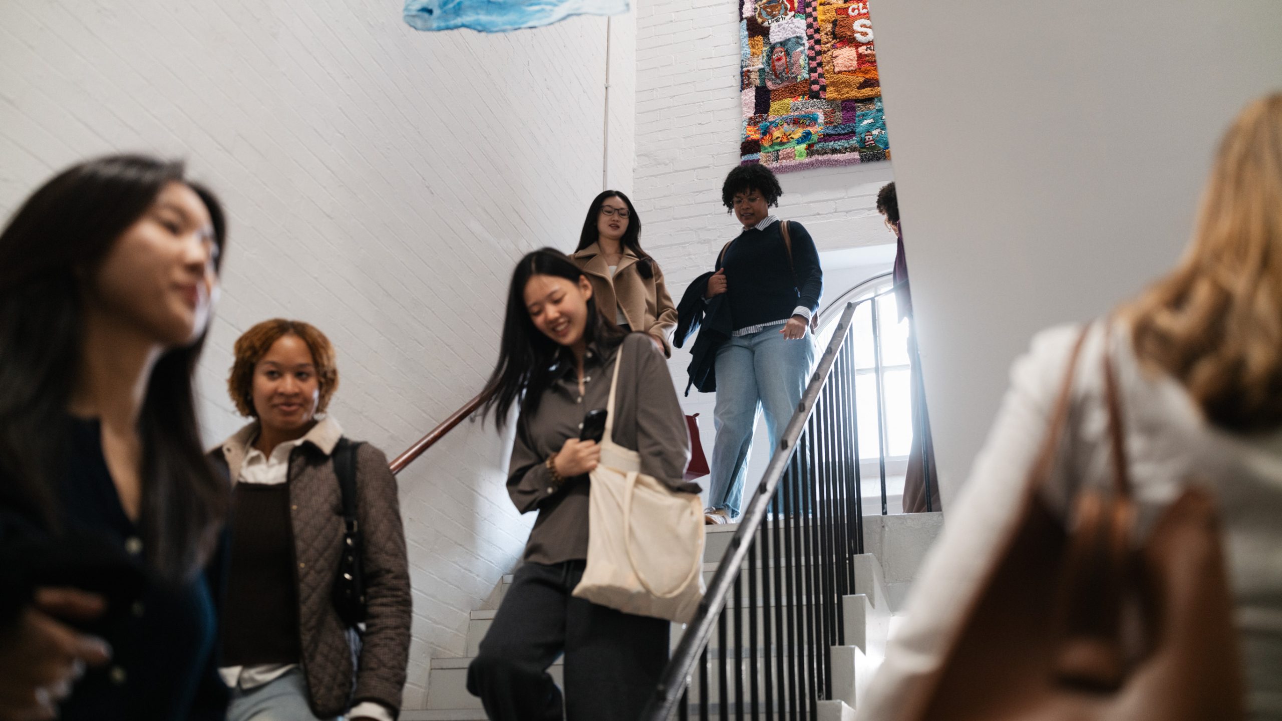 A number of students descend a white staircase at the Courtauld Institute, Vernon Square
