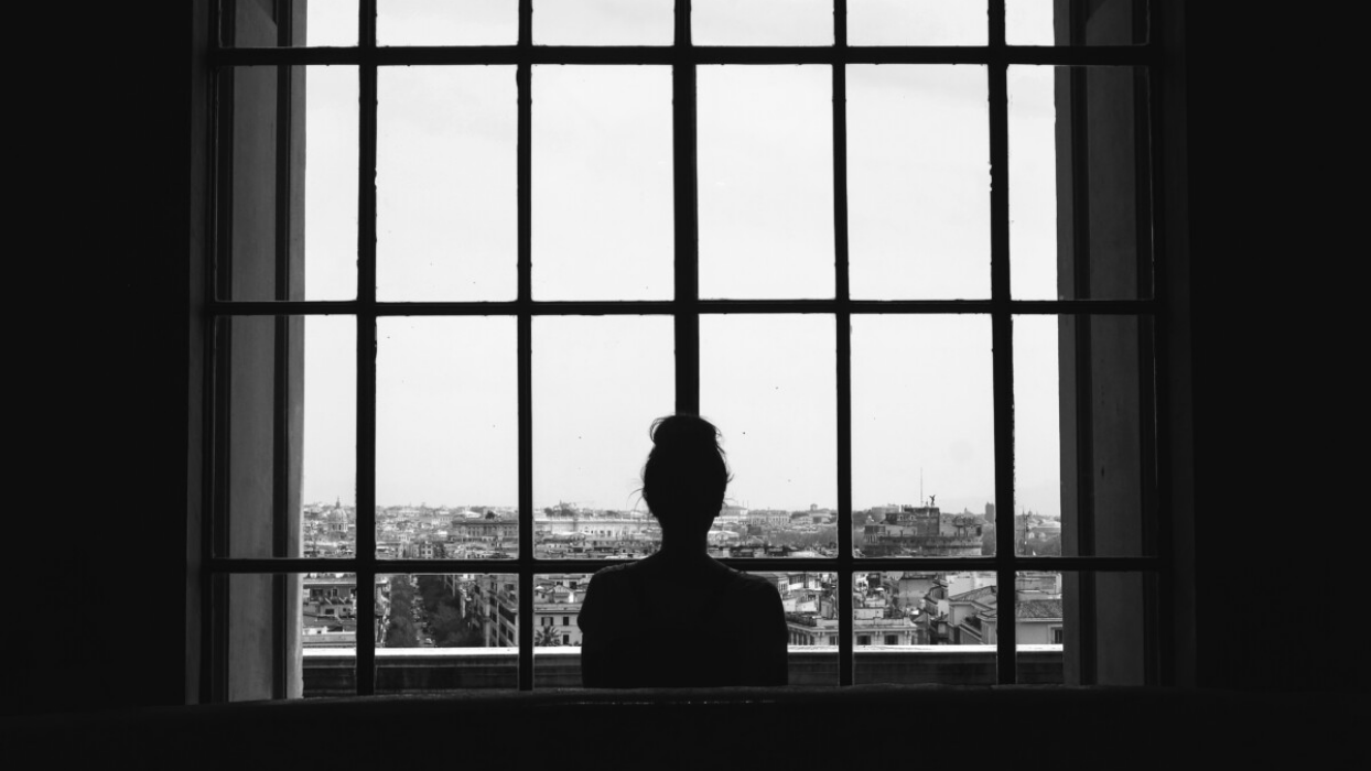 silhouette of a woman looking out of a window.