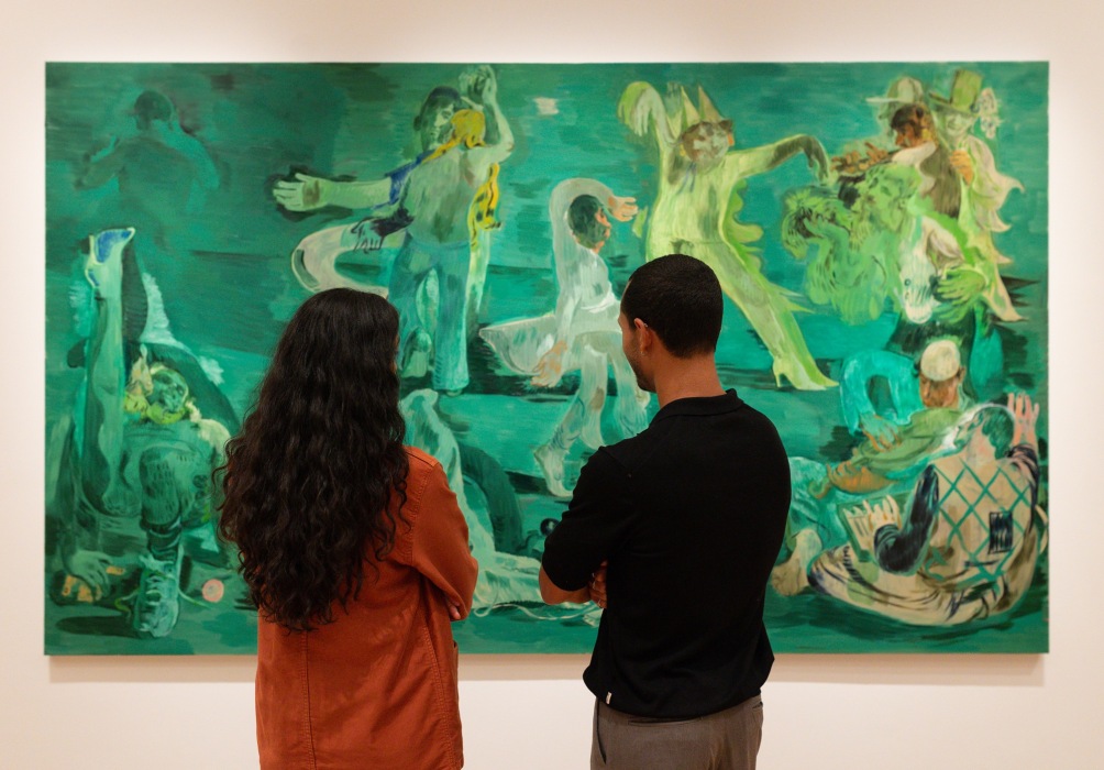 Two people stand in front of Salman Toor's large scale painting, Ghost Ball